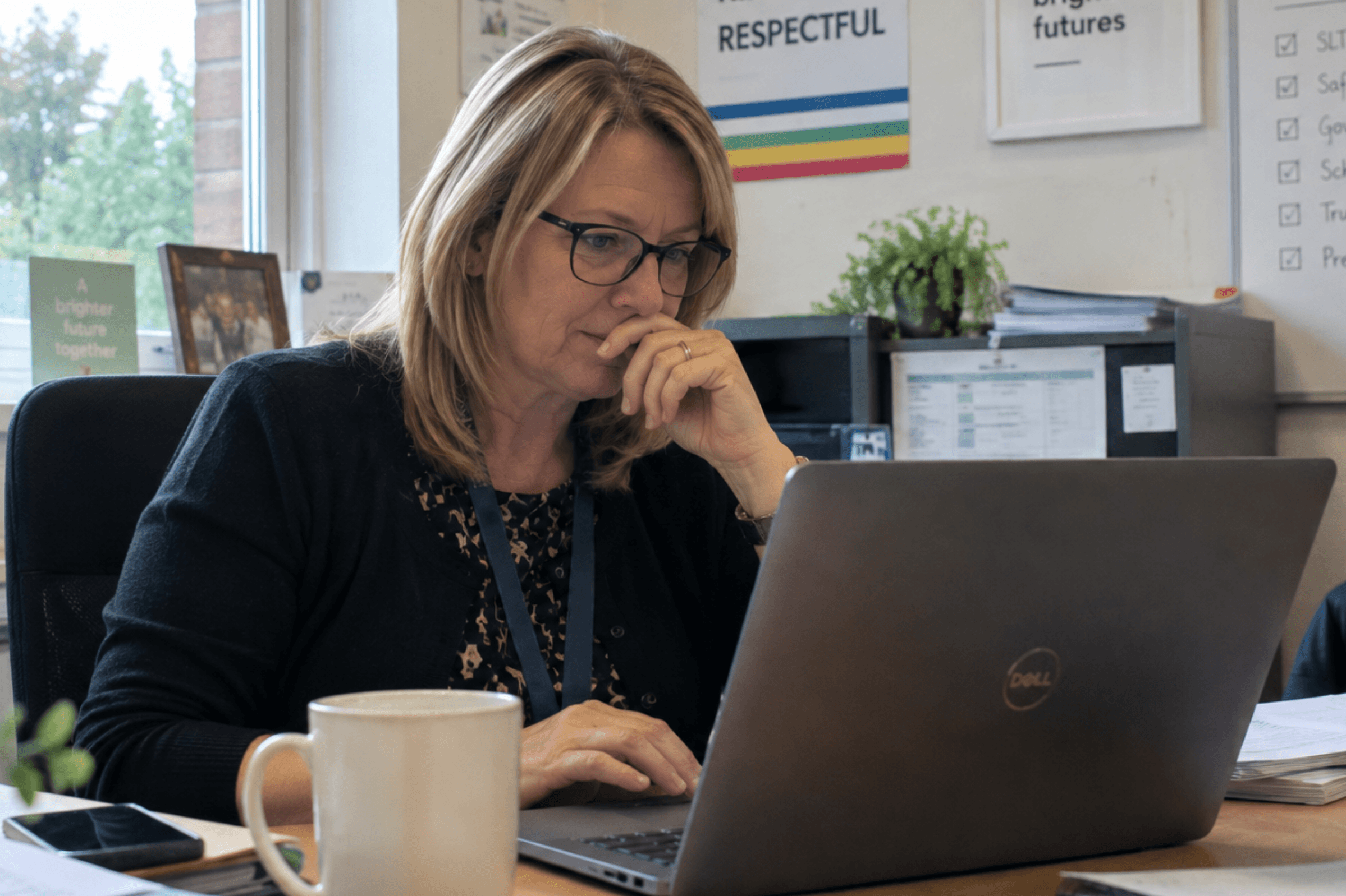Headteacher considering emails on a laptop in a school office